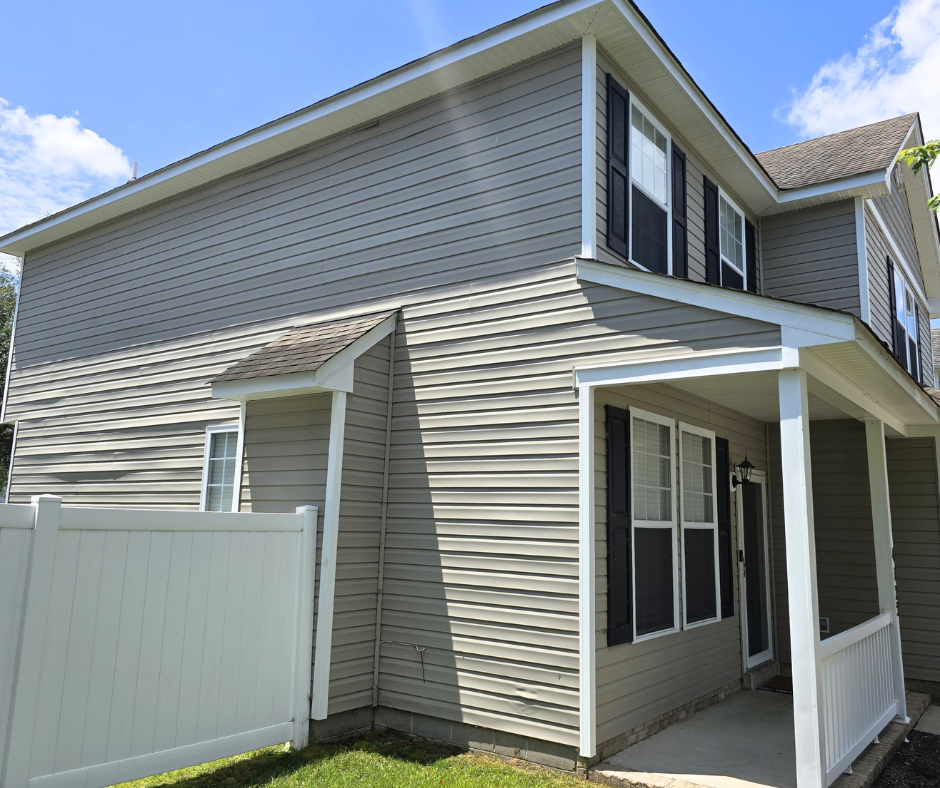 Two-story home with clean vinyl siding, covered front porch, and freshly maintained exterior after professional house washing service.