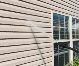 Pressure washing vinyl siding around residential windows to remove dirt, mildew, and exterior buildup.