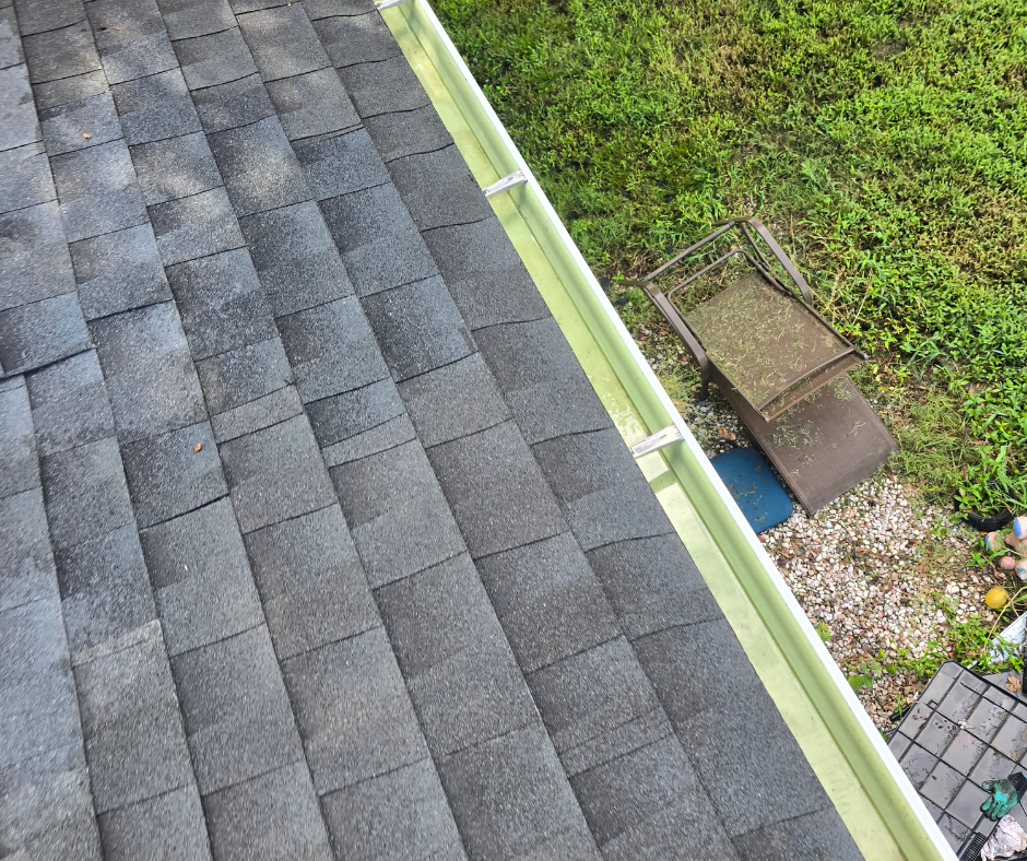 Close-up view of a residential roof with asphalt shingles and a green gutter.
