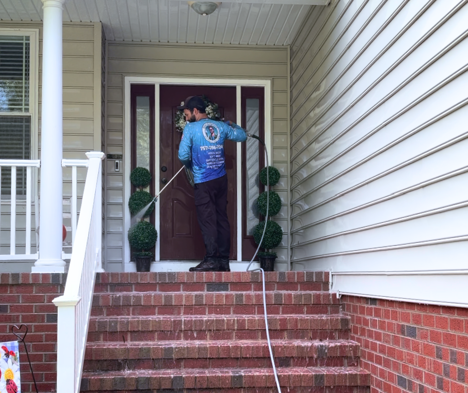 A professional pressure washing technician cleaning the brick front steps of a home, removing dirt and buildup from the entryway.